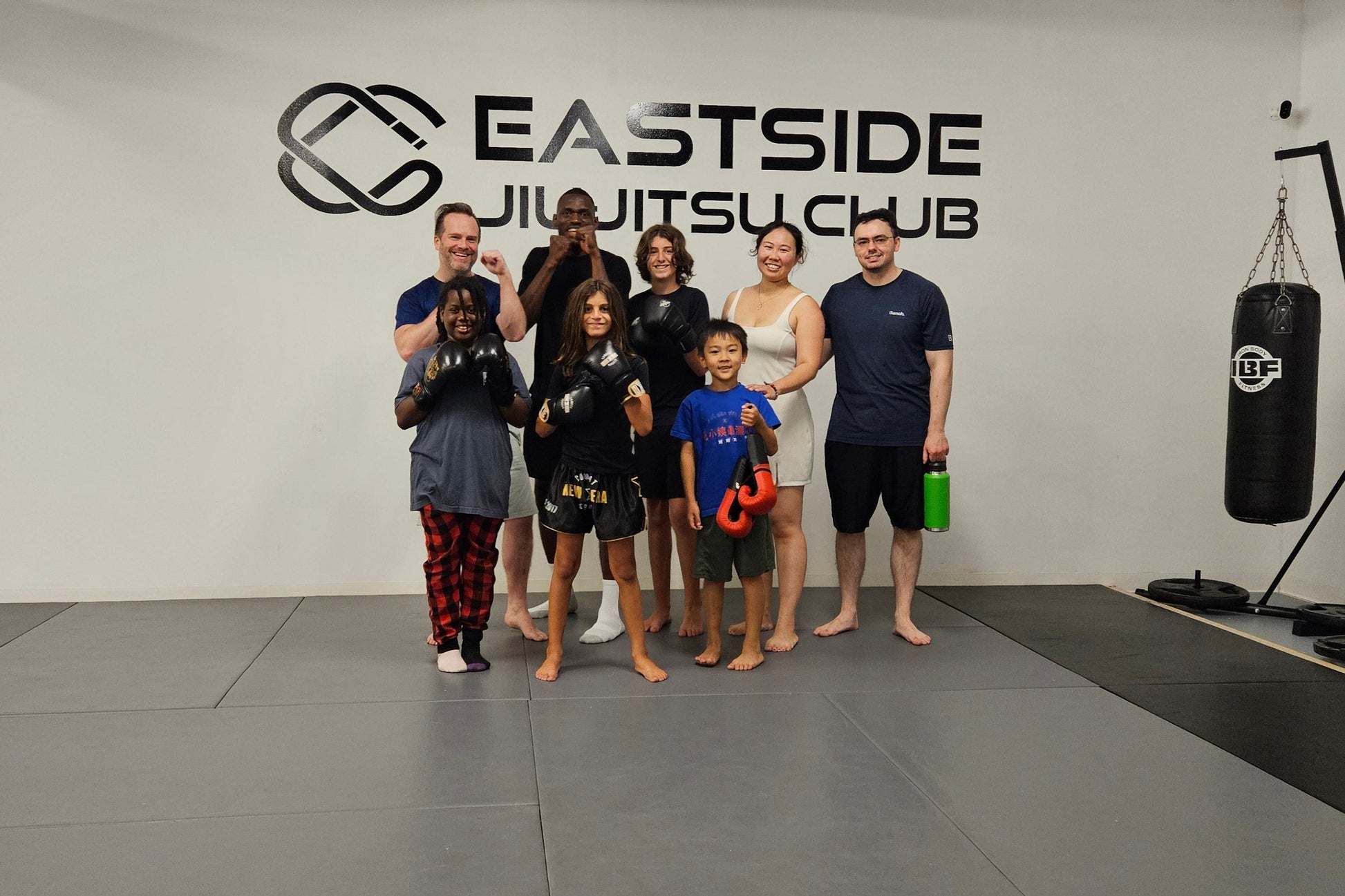 Group of people posing in a room with 'Eastside Jiu-Jitsu Club' branding.