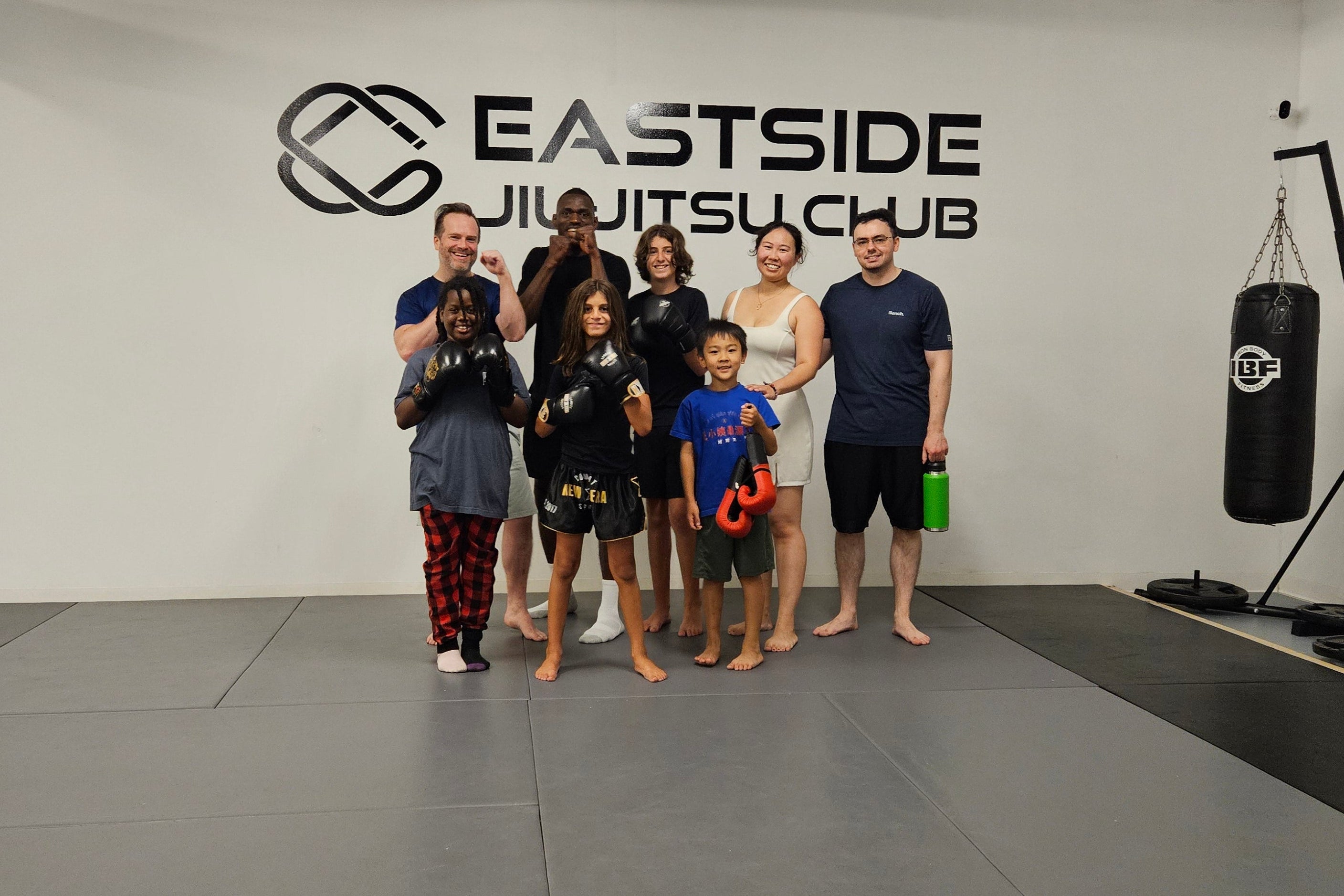 Group of people posing in a room with 'Eastside Jiu-Jitsu Club' branding.