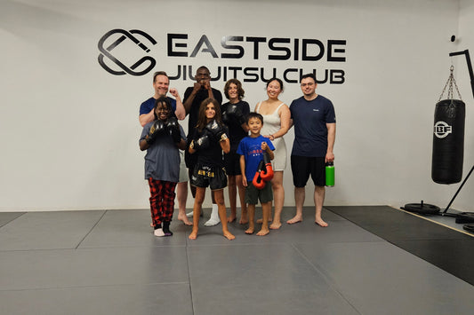 Group of people posing in a room with 'Eastside Jiu-Jitsu Club' branding.
